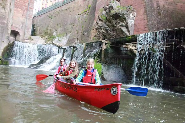 Drei junge Mädchen in einem Kanu unterhalb des Wasserfalls in Saarburg